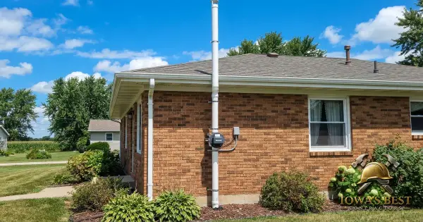 Radon mitigation system PVC vent pipe installed on exterior wall of Iowa home